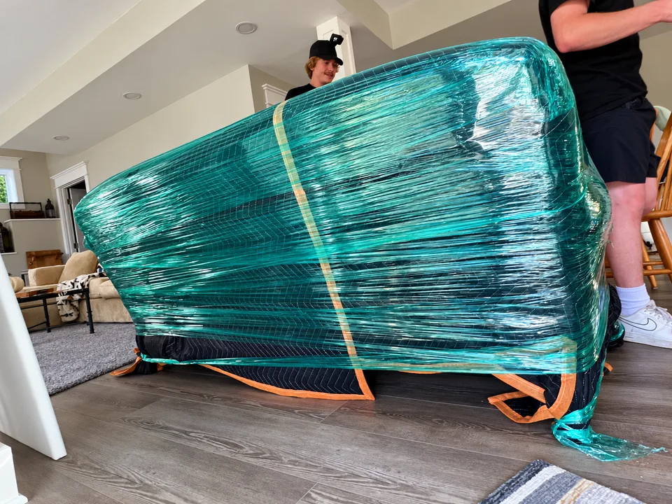 A couch protected with moving blankets, stretch wrap and straps by the Second Chance crew